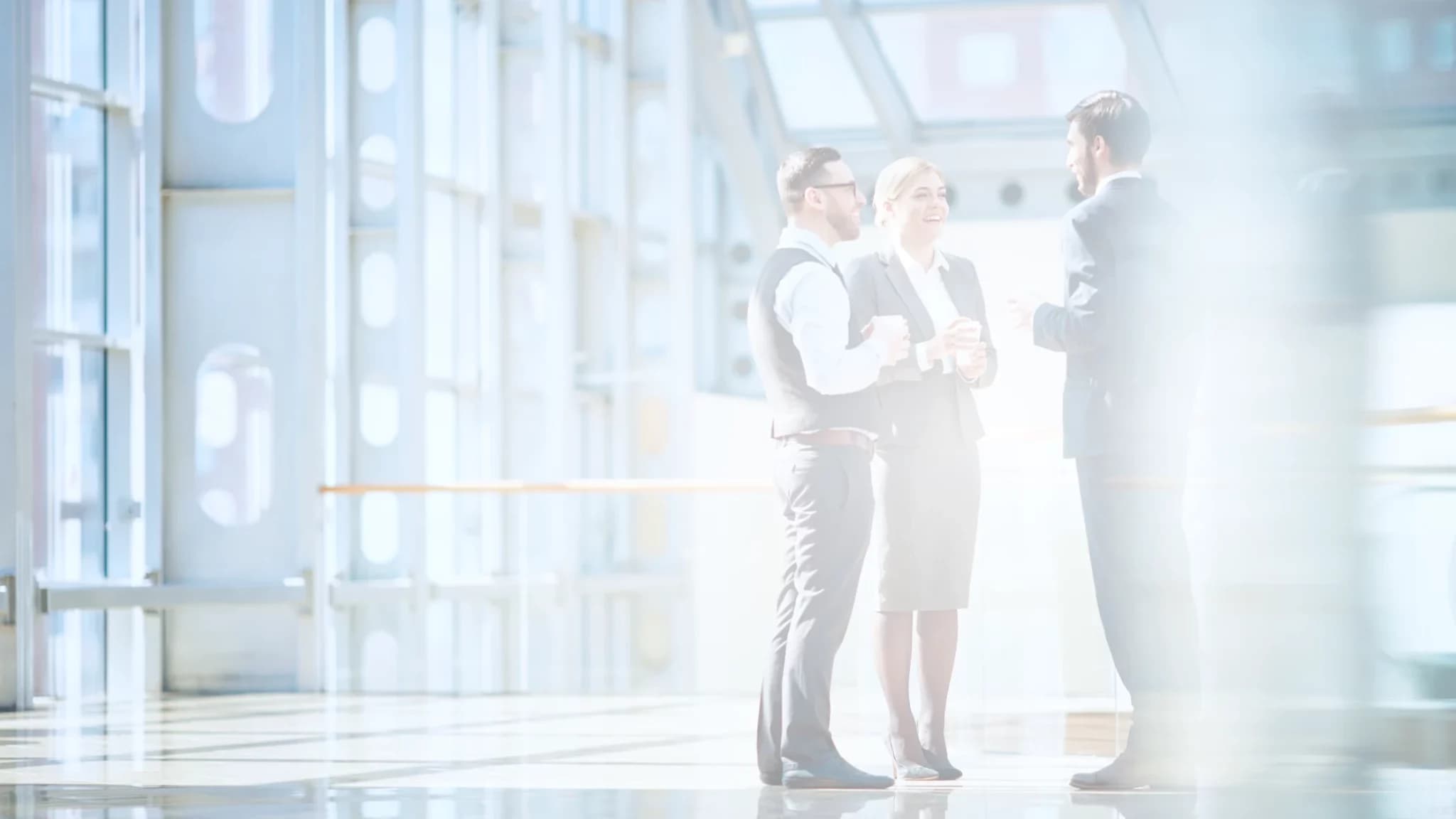 People standing in a group talking in the entrance hall of an office building.